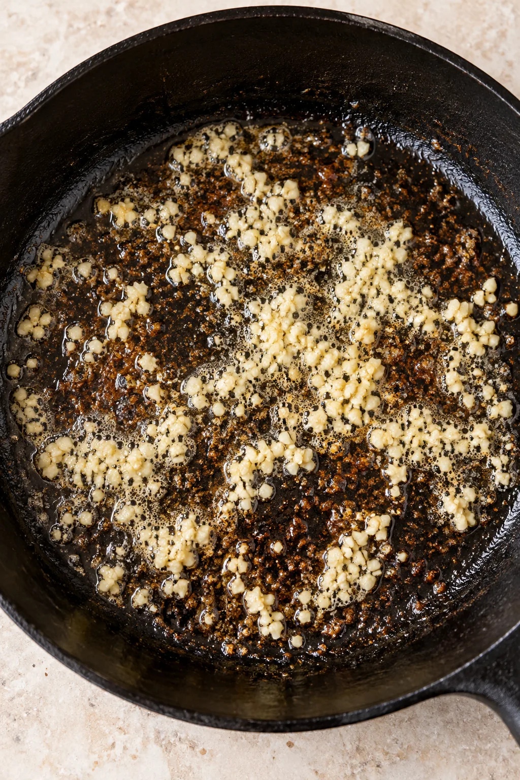 Minced garlic cooking in butter with browned steak drippings in the skillet.