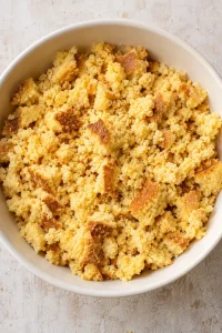 Crumbled yellow cornbread in a ceramic mixing bowl