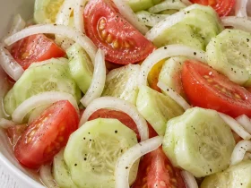 Marinated cucumber rounds, tomato wedges and white onion rings in a vinegar dressing.