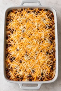 Assembled casserole topped with shredded Colby Jack before baking