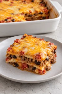 A square serving showing corn tortilla, beef, black bean, and cheese layers