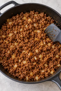 Taco-seasoned ground beef and softened diced onion in a skillet with very little loose liquid