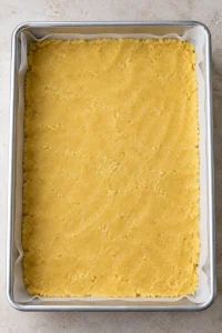 Yellow cake-mix dough pressed across the bottom of a lined baking pan