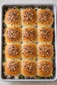 Connected dinner roll tops brushed with melted butter and everything seasoning before the final bake