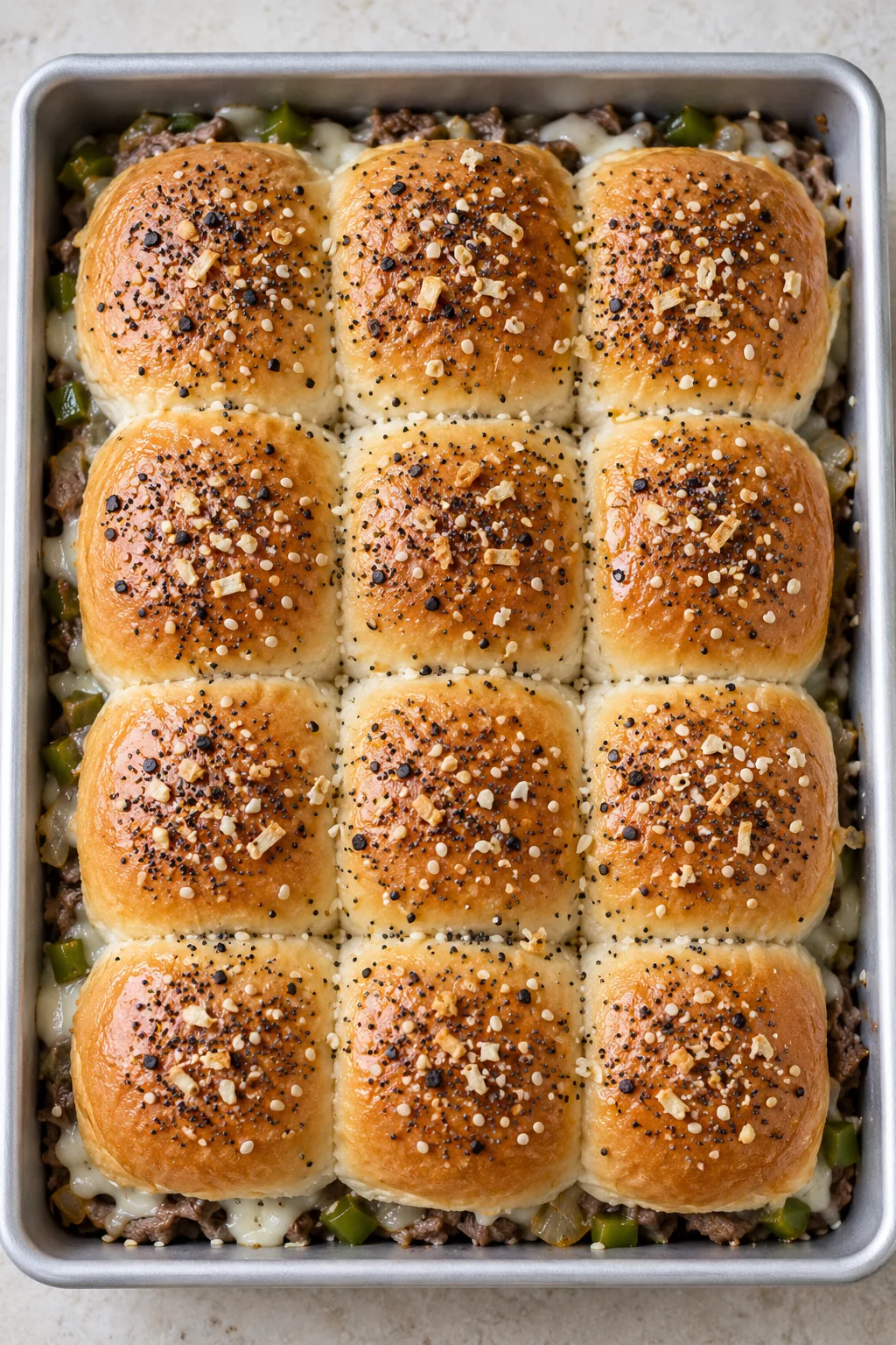 Connected dinner roll tops brushed with melted butter and everything seasoning before the final bake
