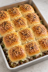 A whole tray of twelve Philly cheesesteak sliders with an everything-seasoned butter topping