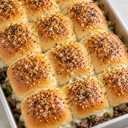 A whole tray of twelve Philly cheesesteak sliders with an everything-seasoned butter topping