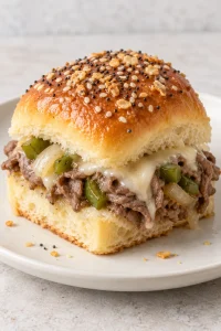 One small Philly cheesesteak slider showing shaved roast beef, melted provolone, and bell pepper