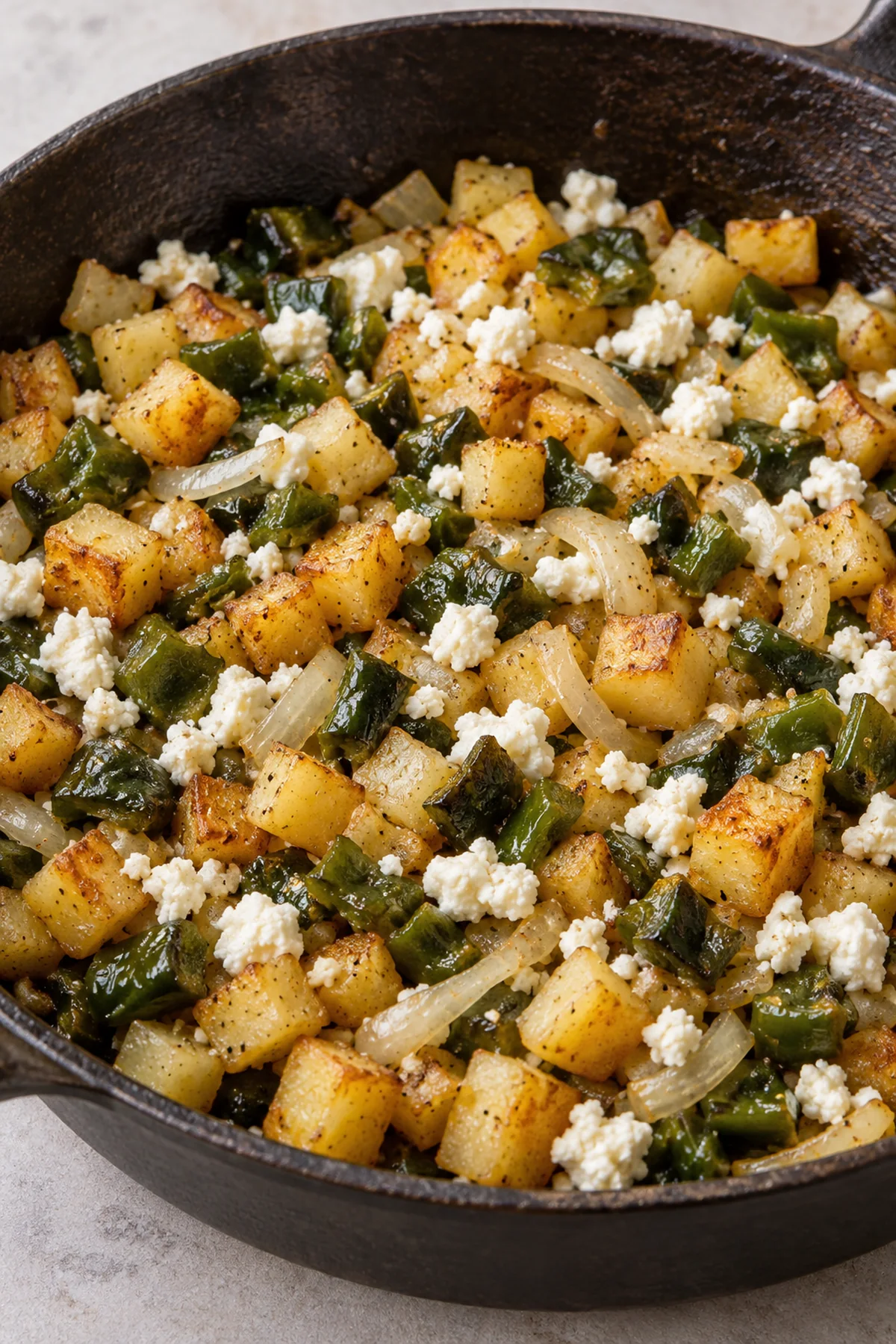 Browned potato and poblano taco filling mixed with queso fresco in a skillet