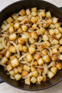 Diced boiled potatoes and sliced onion browning in olive oil