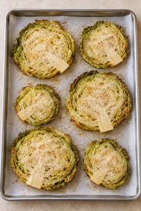 Partly roasted cabbage steaks topped with a thin layer of finely grated Parmesan before the final bake