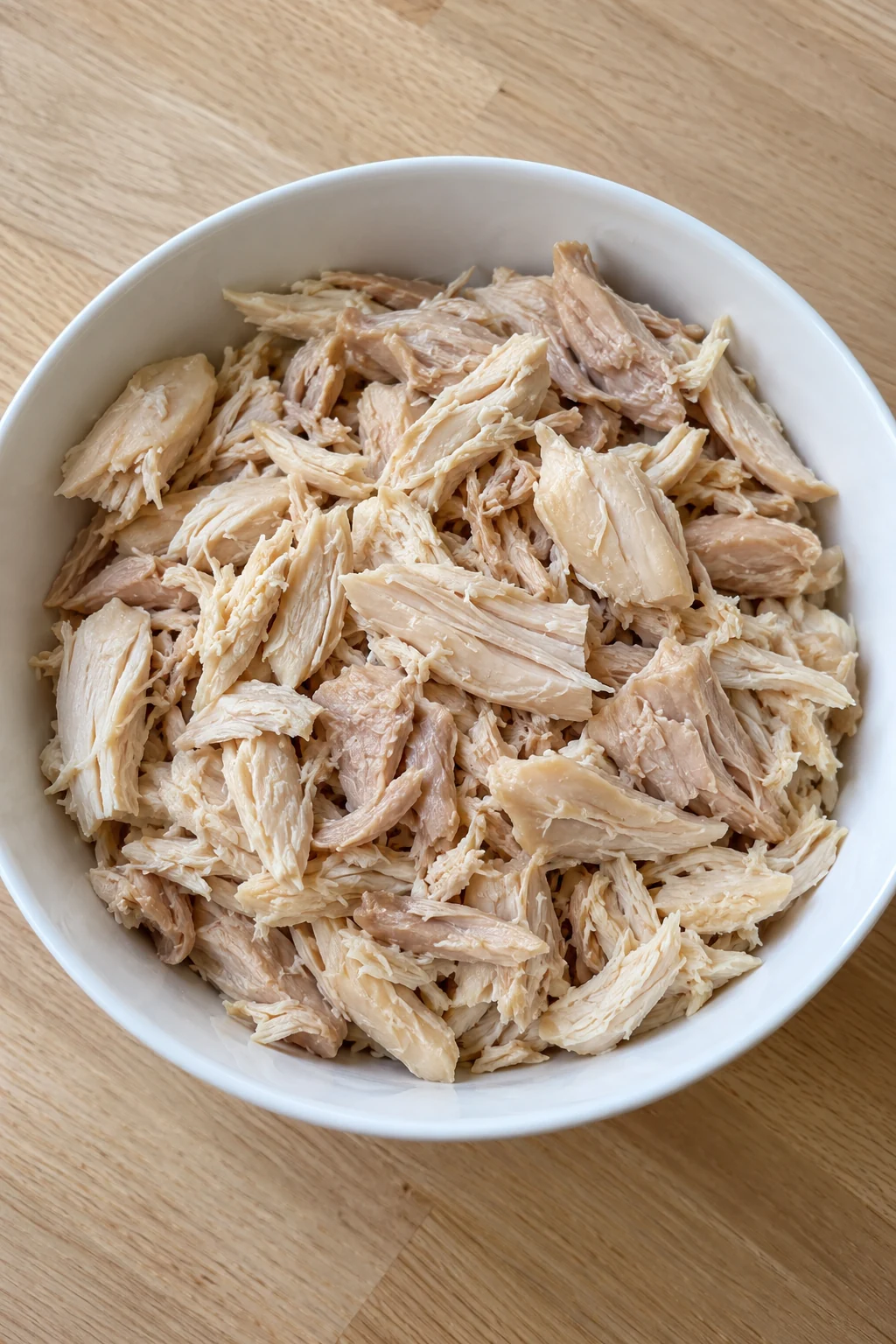 Bite-size shredded rotisserie chicken with the skin and bones removed in a white bowl
