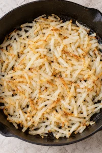 Shredded hash browns softened and lightly browned in a skillet