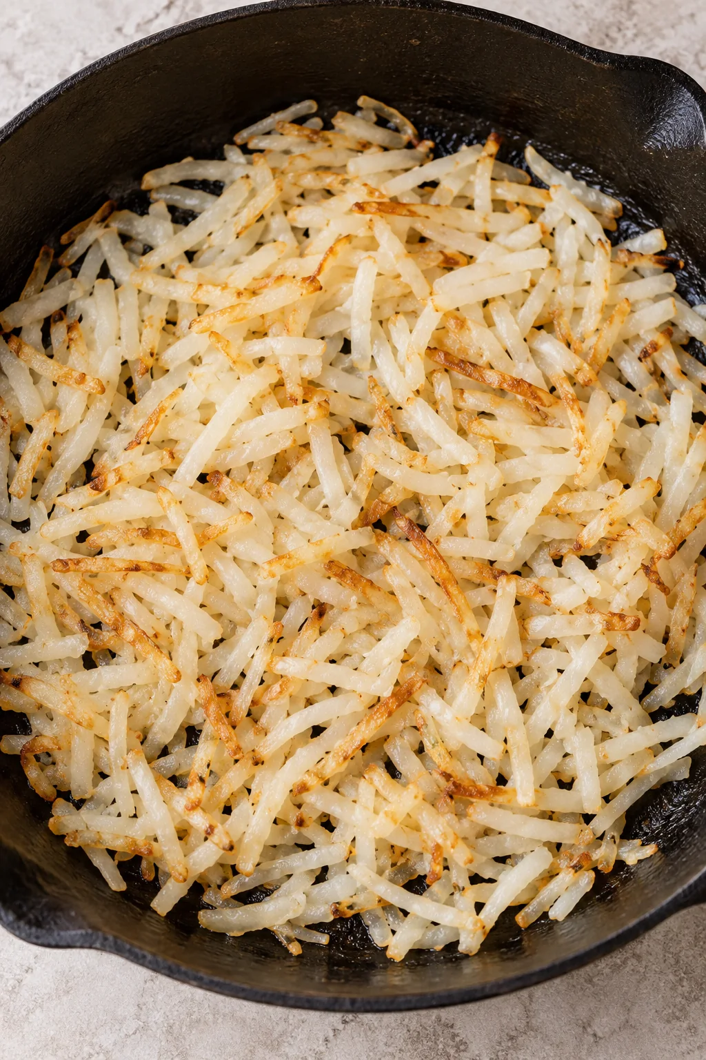 Shredded hash browns softened and lightly browned in a skillet