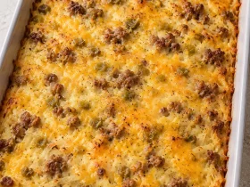 Whole baked sausage hashbrown casserole with cheddar and green chiles in a gray dish
