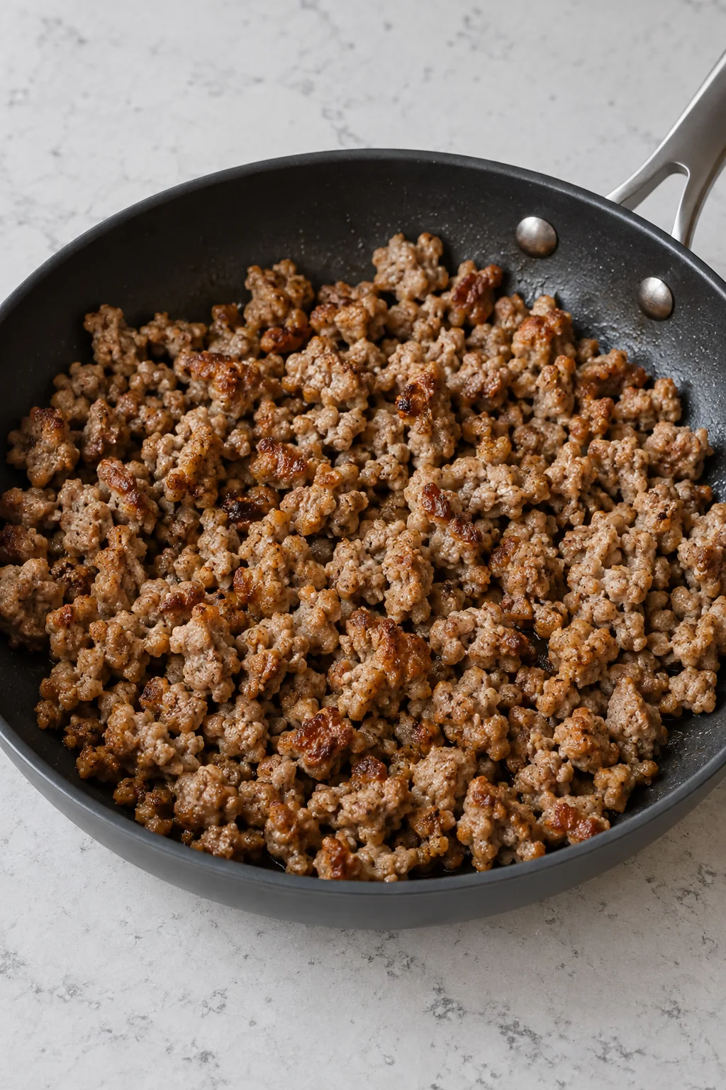 Cooked pork sausage broken into small browned crumbles in a skillet