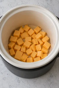 Processed cheese cubes placed in the bottom of a small slow cooker