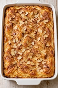 Overhead view of baked sopapilla cheesecake with golden pastry and toasted almonds.