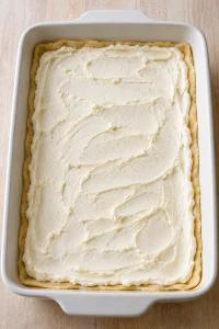 Cream cheese filling spread evenly over the bottom crescent dough layer.
