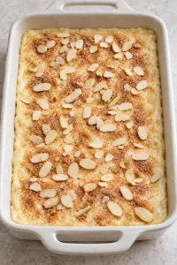 Unbaked sopapilla cheesecake topped with cinnamon sugar and sliced almonds.