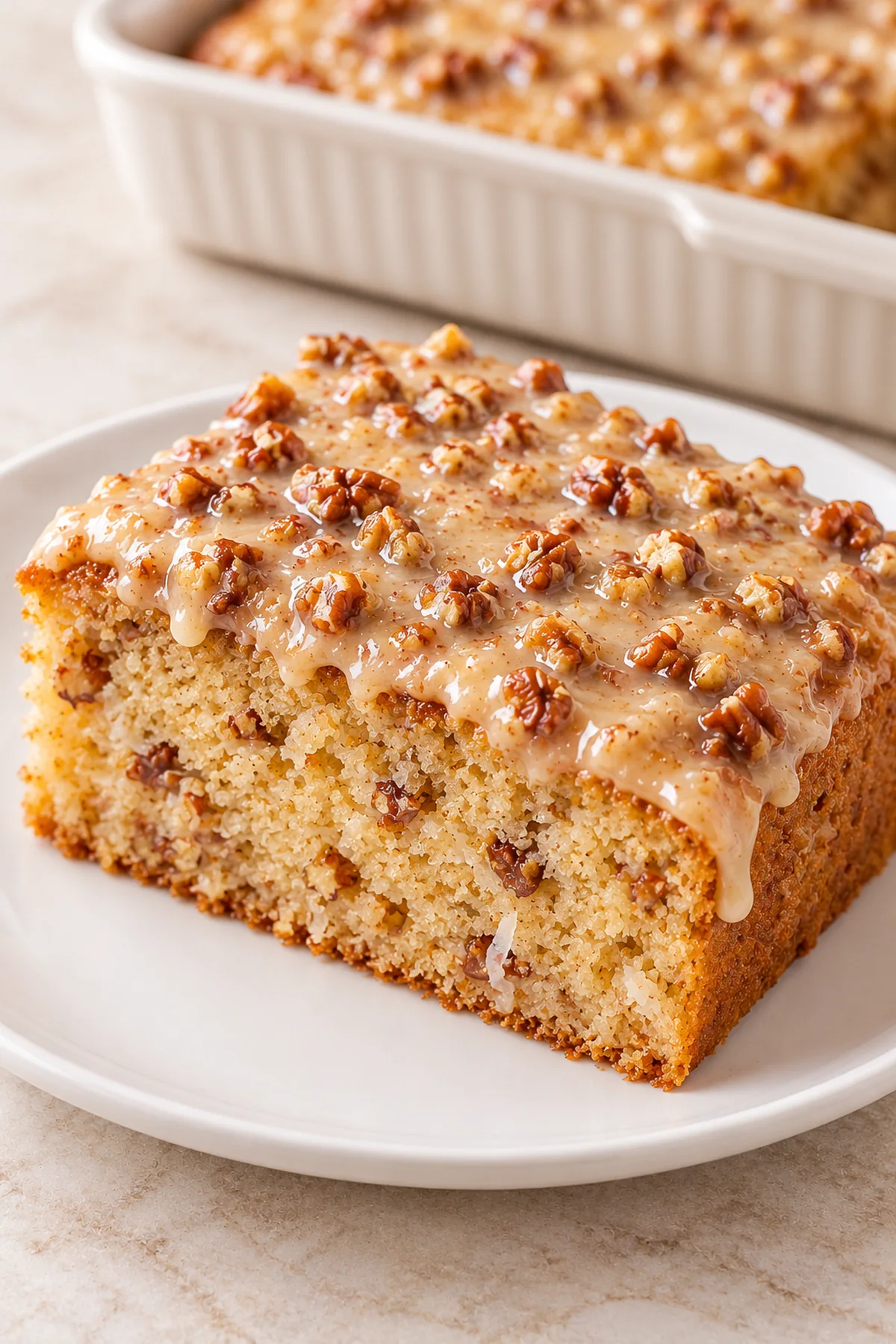 A slice of butter pecan sheet cake showing the soft crumb beneath the pecan glaze