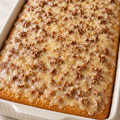 Southern pecan praline sheet cake with butter pecan glaze in a white baking dish
