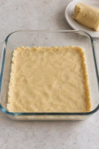 An even layer of raw sugar cookie dough pressed into an 8-inch square glass baking dish