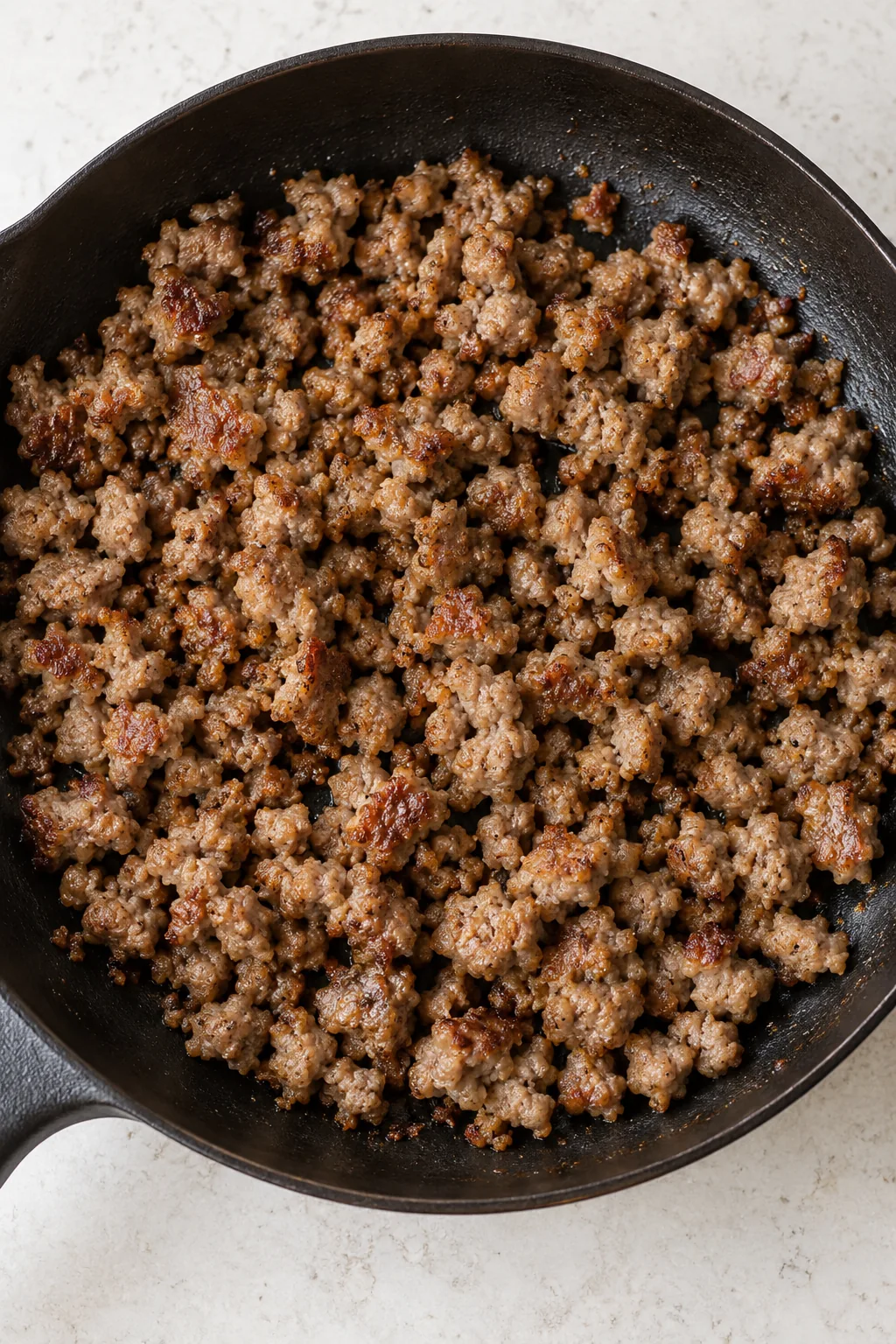 Cooked crumbled breakfast sausage in a skillet for the casserole