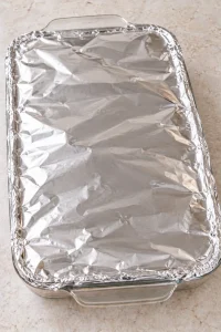 Glass baking dish of teriyaki chicken casserole covered tightly with foil before baking