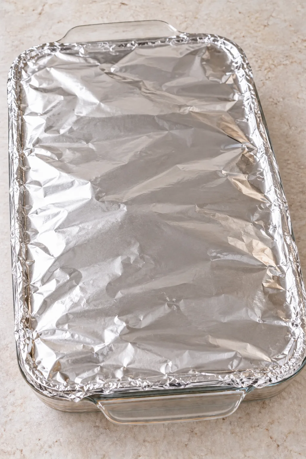 Glass baking dish of teriyaki chicken casserole covered tightly with foil before baking