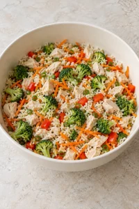 Cooked white rice and diced chicken mixed with broccoli, red pepper and shredded carrots before adding sauce