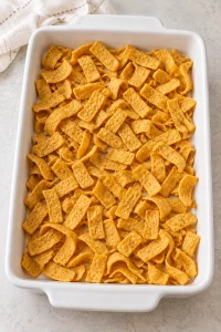Half the corn chips spread in a rectangular baking dish for the casserole base