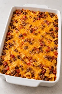 Baked walking taco casserole with melted cheddar before the fresh toppings are added